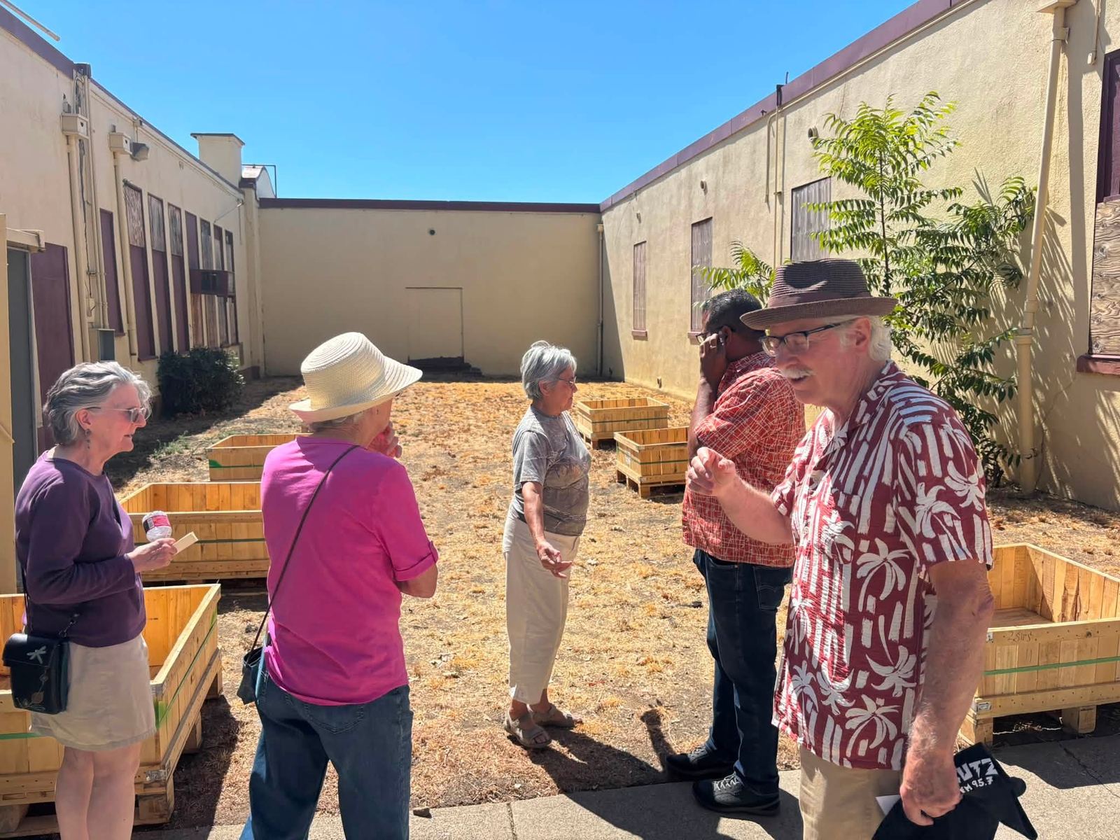 Neighbors standing among new wooden planter boxes in the courtyard