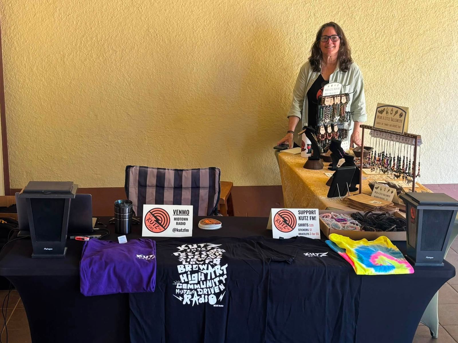 The KUTZ community radio table with t-shirts and speakers